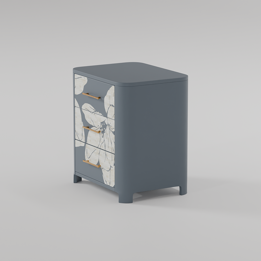 A modern three-drawer nightstand in slate blue with white floral inlays on the drawer fronts and slim gold handles, shown on a neutral gray background.