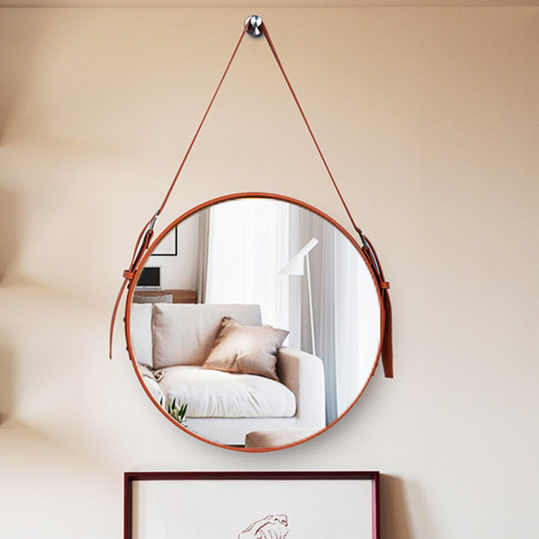 "Round vanity mirror with a leather-trimmed frame, perfect for bathrooms and bedrooms."