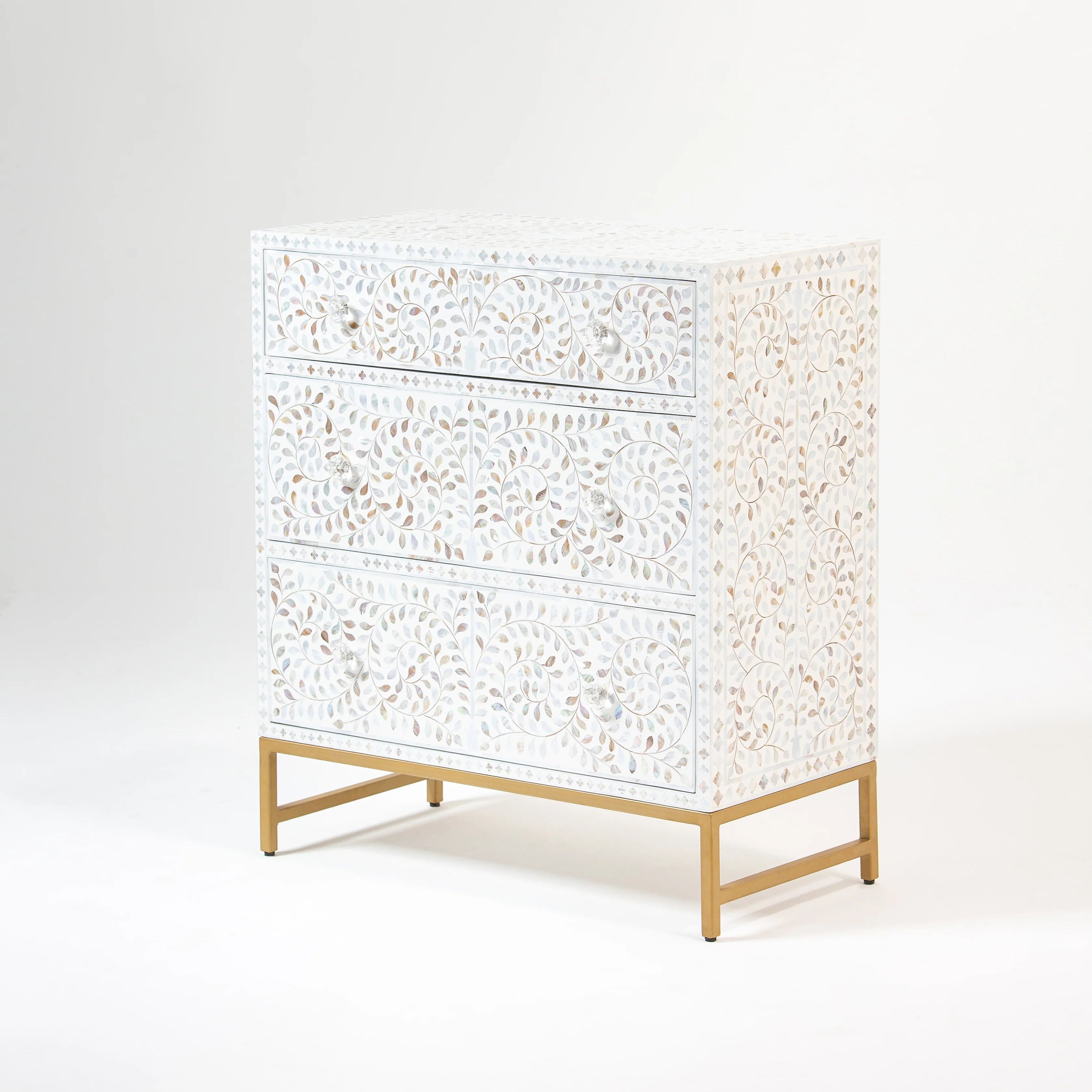 Side view of a bone inlay dresser with intricate swirl and leaf patterns, resting on a sleek gold metal frame.