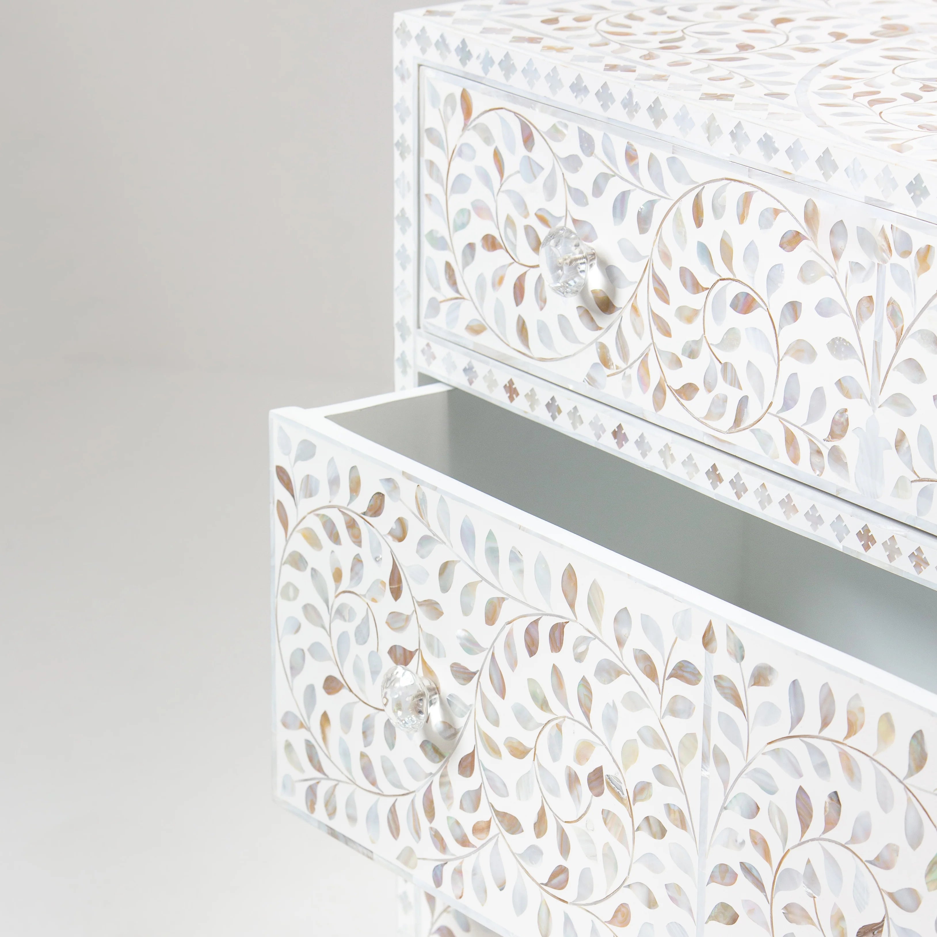 Close-up of a drawer from a bone inlay cabinet, showcasing intricate swirl and leaf patterns, with the drawer partially open