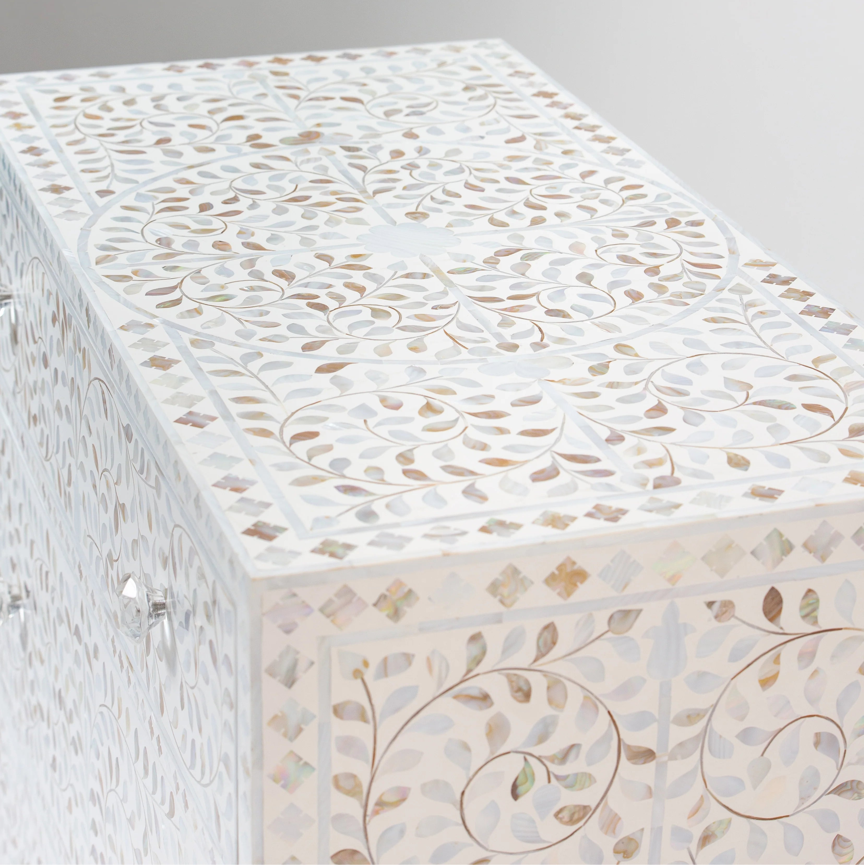 Close-up of a decorative table featuring a mosaic pattern with intricate swirl and leaf designs on a plain background.
