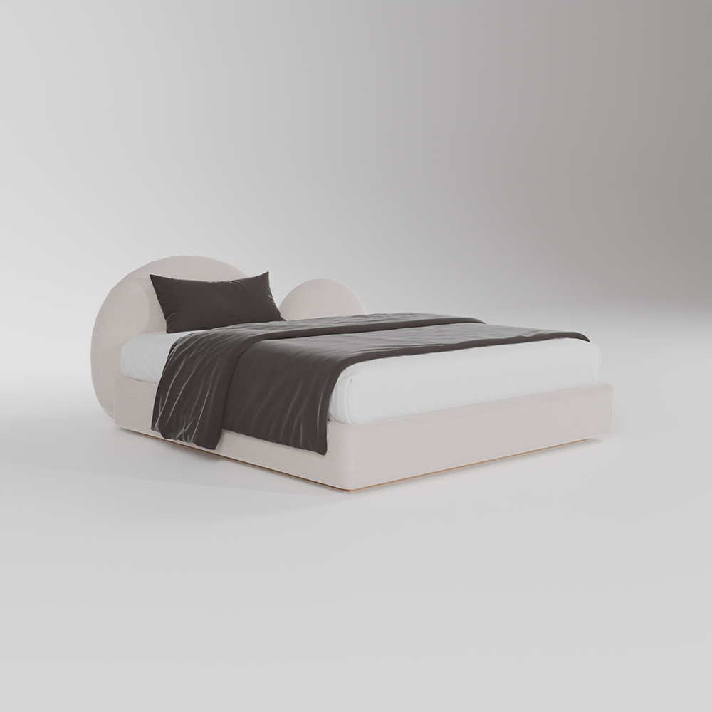 A modern low-profile platform bed with a rounded, circular headboard and matching footboard in a light blush pink fabric. The bed is styled with white sheets, a dark charcoal gray throw blanket, and a matching dark gray pillow, set against a seamless light gray studio background.