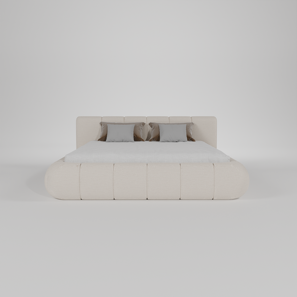 A modern low-profile platform bed with a padded, rounded upholstered base and headboard in a warm off-white or cream fabric, styled with a white mattress and four neutral gray pillows, set against a seamless light gray studio background.