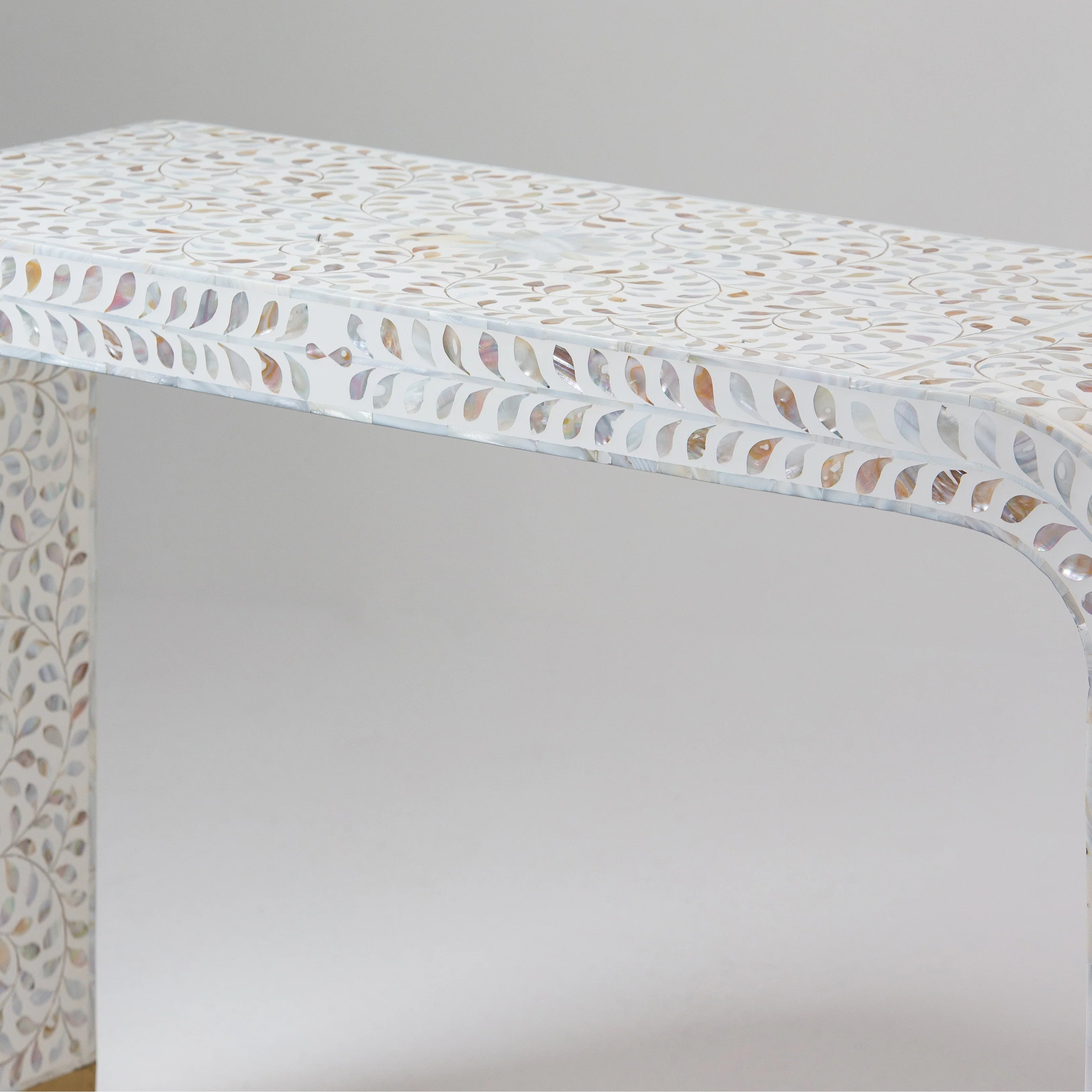Close-up of a bone inlay table with intricate leaf patterns, focusing on the top edge and side details.