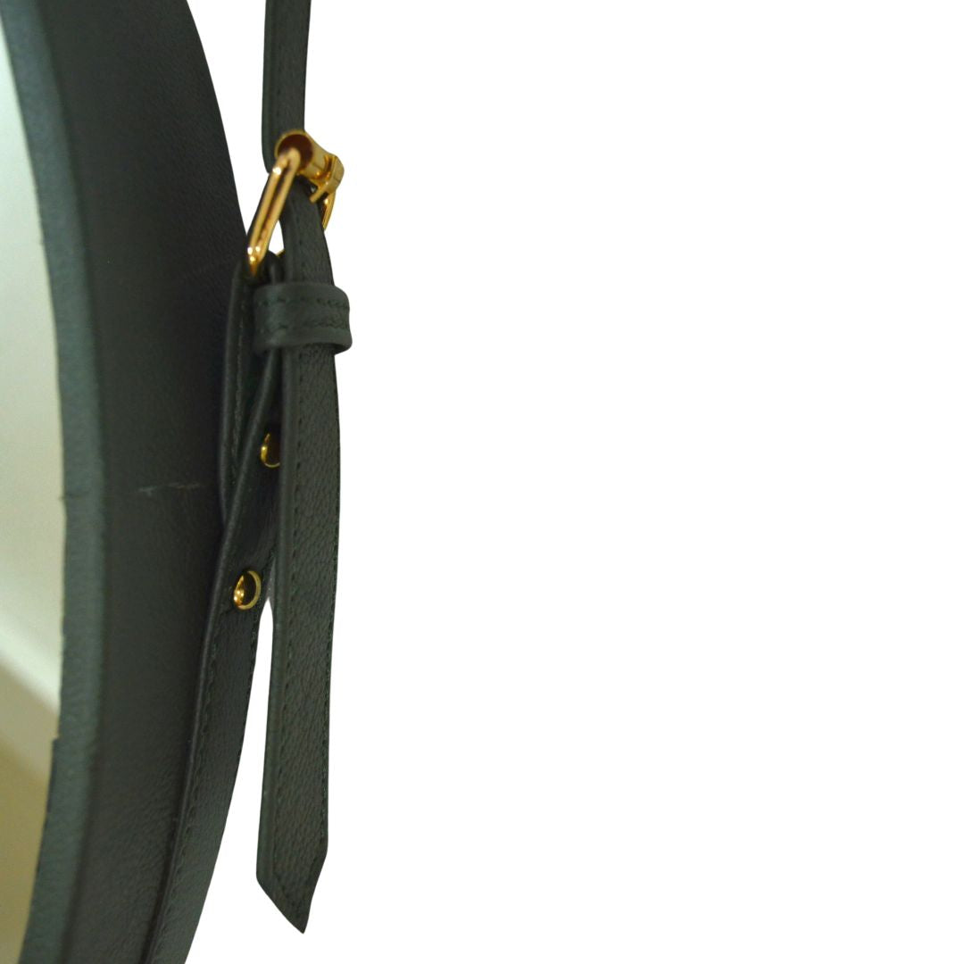 "Round vanity mirror with a leather-trimmed frame, perfect for bathrooms and bedrooms."
